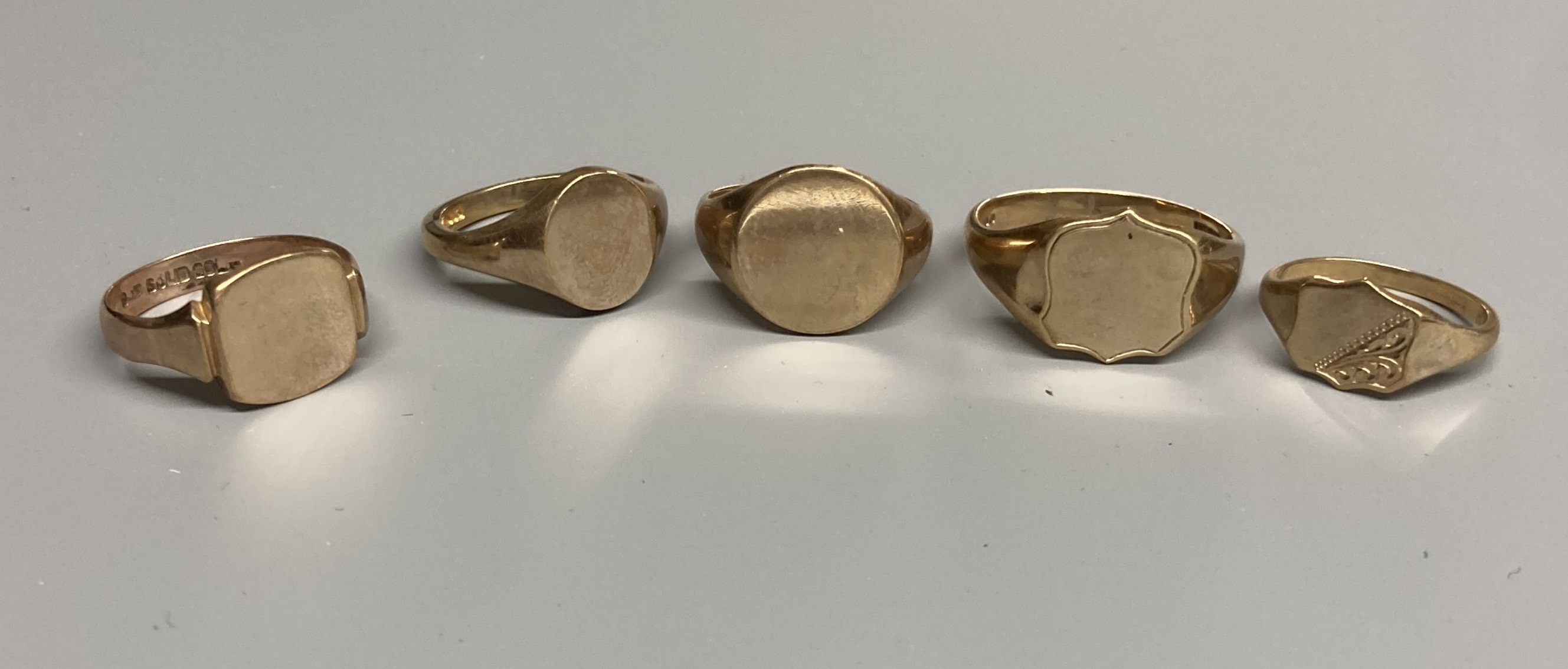 Four assorted modern 9ct gold signet rings and one other similar 9ct ring, largest size V